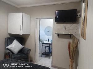 a living room with a tv and a chair at The Hush House in Roodepoort
