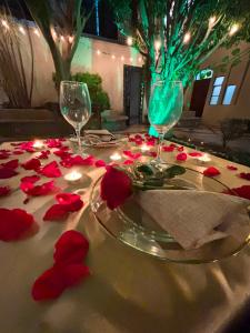 a table with two wine glasses and red rose pedals at Hotel San Jose Centro Historico in San Luis Potosí