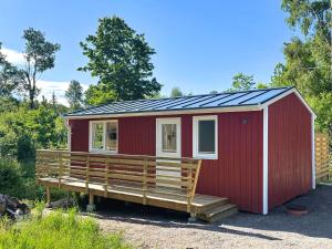 a red tiny house with a large porch at Älg Stuga in Kosta