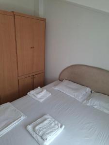 a bed with two towels on it with a cabinet at Apartmani Lazić No 9 in Gracanica