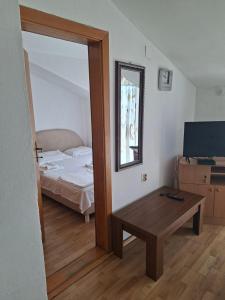 a bedroom with a bed and a table and a mirror at Apartmani Lazić No 9 in Gracanica