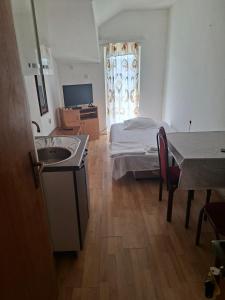 a bedroom with a bed and a sink and a table at Apartmani Lazić No 9 in Gracanica