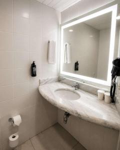 a white bathroom with a sink and a mirror at ibis Santos Gonzaga Praia in Santos +82 photos