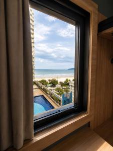 a window with a view of a pool and the beach at ibis Santos Gonzaga Praia in Santos