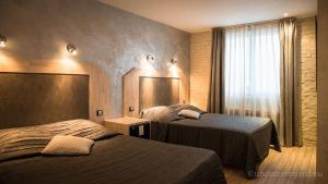a hotel room with two beds and a window at La glycine hotel, spa et bien-être in Bénouville
