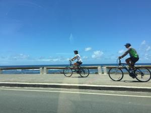 Dos personas en bicicleta por un camino cerca del océano en Apartamento Oceano Atlantico, en Salvador