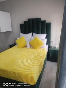 a bedroom with a bed with yellow and white pillows at The Hush House in Roodepoort +10 photos