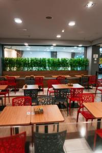 a restaurant with wooden tables and red chairs at ibis Santos Gonzaga Praia in Santos