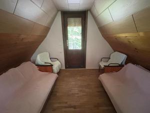 a room with two beds and a window and a door at Vikendica in Bezdan