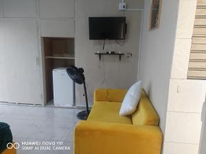 a living room with a yellow couch and a tv at The Hush House in Roodepoort