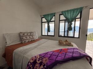 a bedroom with a bed and two windows at Casa Miralagos in Santa Cruz La Laguna