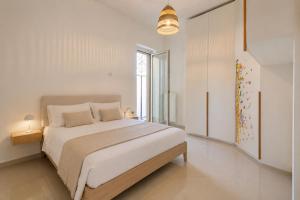 a white bedroom with a large bed and a window at Wanderlust Experience La Casetta in Bitonto
