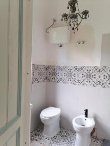 a white bathroom with a toilet and a chandelier at La Raccolta in Scheggino