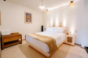 a bedroom with a large white bed and a table at Hotel Casa Eteca in San Pedro y San Pablo Etla