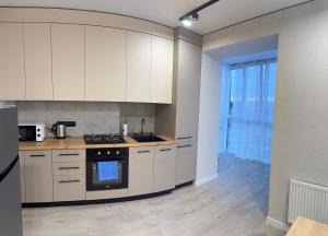 a kitchen with white cabinets and a stove top oven at Dream 71 in Lutsk +6 photos
