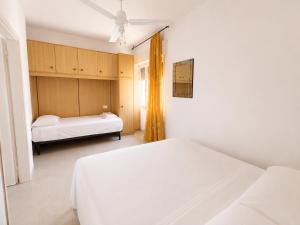 a white bedroom with two beds and a window at Anthea- Paluzza Apartment & Parking in Lignano Sabbiadoro