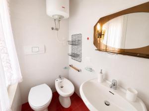 a white bathroom with a toilet and a sink at Anthea- Paluzza Apartment & Parking in Lignano Sabbiadoro