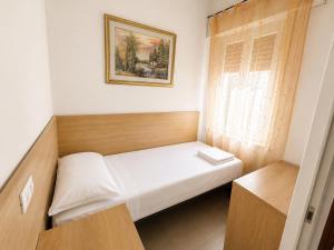 a small bed in a small room with a window at Anthea- Paluzza Apartment & Parking in Lignano Sabbiadoro