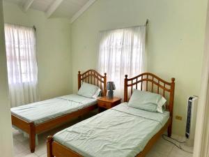 two beds in a room with two windows at Tropical Retreat - by ZenBreak in Saint Peter