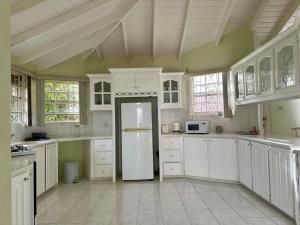 a large kitchen with white cabinets and a white refrigerator at Tropical Retreat - by ZenBreak in Saint Peter