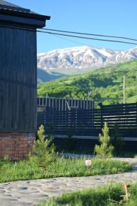 a house with a fence and mountains in the background at Shahdag Berghoff Villas in Qusar