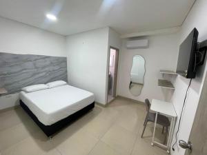 a bedroom with a bed and a tv and a chair at karolina Real Hotel Experience in Apartadó