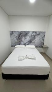 a bed with a bow tie on it in a room at karolina Real Hotel Experience in Apartadó