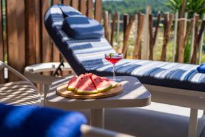 a slice of watermelon on a table with a glass of wine at Petra Nera Skiathos, Philian Hotels & Resorts in Agia Paraskevi +99 photos
