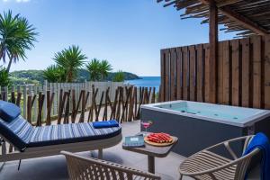a hot tub on a patio with chairs and a table at Petra Nera Skiathos, Philian Hotels & Resorts in Agia Paraskevi