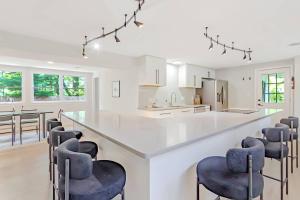 a kitchen with a large white counter with blue bar stools at Modern 3BR With Big Kitchen & TV Rm in State College