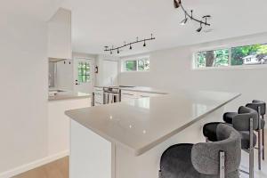 a white kitchen with a large white island with black chairs at Modern 3BR With Big Kitchen & TV Rm in State College +17 photos