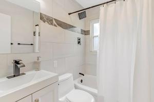 a white bathroom with a sink and a toilet at Modern 3BR With Big Kitchen & TV Rm in State College