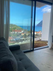 a living room with a couch and a large window at Riba D'Mar - B in Machico