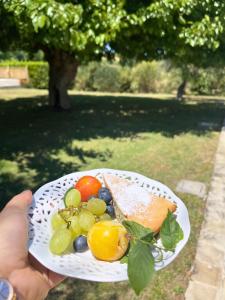 a person holding a plate of food with grapes and toast at Audaces Resort in Recanati