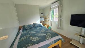 a bedroom with a bed with a blue comforter and a television at Bamboo Khiri in Sathani Rot Fai