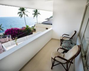 a balcony with two chairs and a view of the ocean at Swapnatheeram Beach Resort in Kovalam