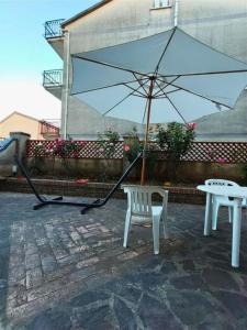 a white bench and an umbrella on a patio at EffeVi - Bed and Books in Piaggine