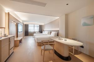 a hotel room with a bed and a table at Zhangjiajie JI Hotel- New hotel, Free pick up service, Free shuttle service for Tianmen Mount Cableway, Smart Hotel&Root Service,King Koil mattress, Free self-service laundry,Toursim Service&English Customer Service in Zhangjiajie +46 photos