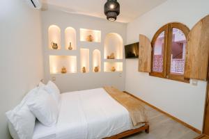 a bedroom with a white bed and some shelves at Hotel Casa Eteca in San Pedro y San Pablo Etla