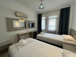 a hotel room with two beds and a mirror at Ünlü Otel in Fethiye