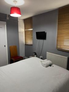 a bedroom with a white bed and a television at Sterling Lodge Hotel in Eastbourne