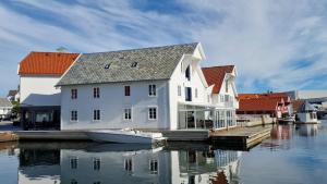 a large white house with a boat in the water at Havn Hotell og Restaurant in Skudeneshavn