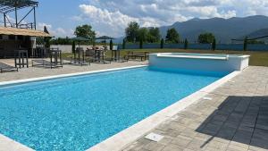a blue swimming pool with mountains in the background at Resort Big House Plitvička jezera in Ličko Petrovo Selo