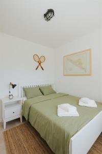 a white bedroom with a large bed with green sheets at Captain`s Cottage in Kaštela