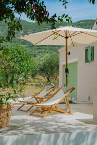 a pair of lounge chairs and an umbrella at Captain`s Cottage in Kaštela