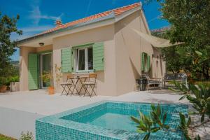 a villa with a swimming pool in front of a house at Captain`s Cottage in Kaštela