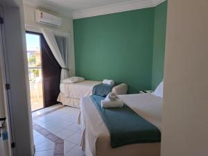 a small room with two beds and a window at Pousada Zamberlan in Guarujá