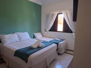 a bedroom with two beds and a window at Pousada Zamberlan in Guarujá