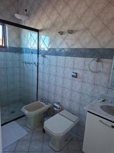 a bathroom with a toilet and a shower and a sink at Pousada Zamberlan in Guarujá