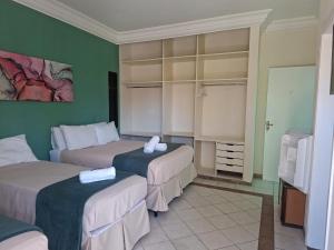 two beds in a room with green walls at Pousada Zamberlan in Guarujá